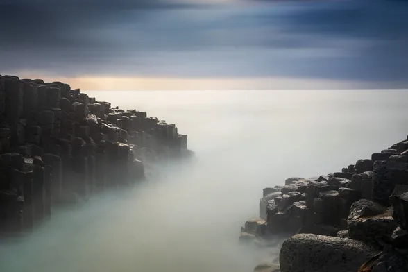 long exposure minimalist seascape with since basalt rocks on the side and smooth sea during the sunrise