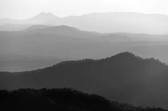 black and white layered mountains covered in fog or smoke in Lamington, QLD