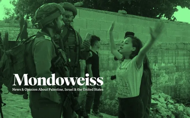 A young Palestinian girl stands in front of two Israeli soldiers who have entered her village in the occupied West Bank. She has her hands raised and is blocking their path. One soldier seems amused and is photographing her with his cell phone.