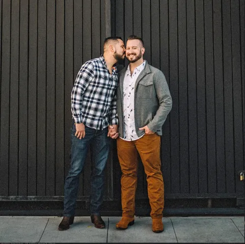 Me and my Husband Brandon during our Save the Date photo session. Jorge is kissing Brandon on the cheek.