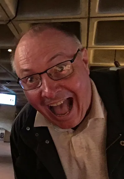 A very manically-delighted, aging, balding, white male in a photo taken at the Friday Daytime Playtest meetup in the National Theatre, from when I lived in London and was able to attend such things.