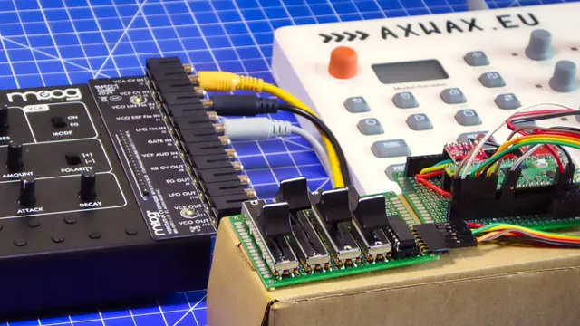 A Moog Werkstatt-01 synth is connected to a PCB containing a Raspberry Pi Pico and two DACS, placed precariously on top of a cardboard box.

The PCB is also connected to a second PCB populated with four sliders and an IC. 

In the back an Elektron Model:Samples groovebox can be seen, which is hooked up to the Pico via MIDI (not pictured).