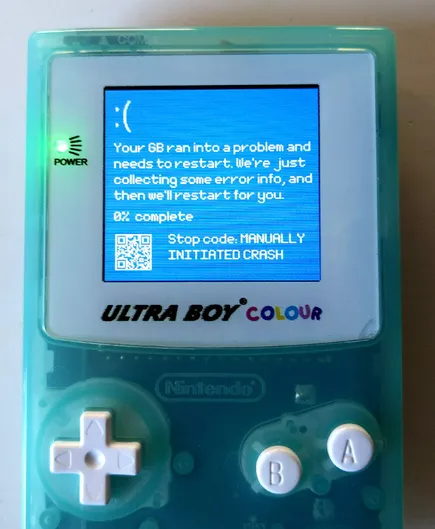 Photograph of a game boy showing a windows blue screen error, a qr code and the text: :( Your GB ran into a problem and needs to restart. We're just collecting some error info, and we'll restart for you.
0% complete
Stop code: MANUALLY INITIATED CRASH