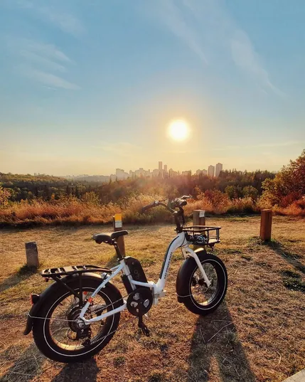 An ebike on a sunny day in the late afternoon, in front of the Edmonton skyline. The vibe is golden, fall-like.