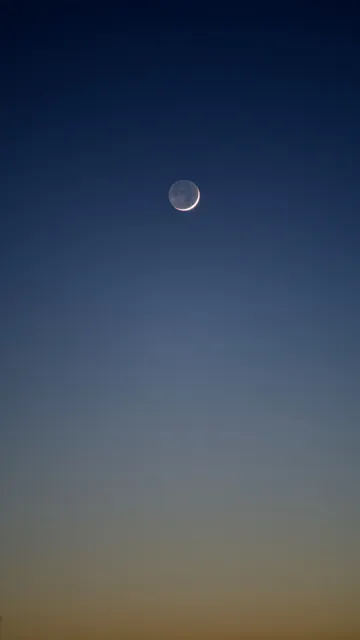 A 2-day old moon right before sunset. The bright shine of the Earth illuminating the dark side.