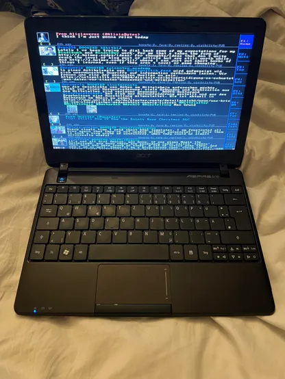 A small black netbook running a text GUI application fullscreen.