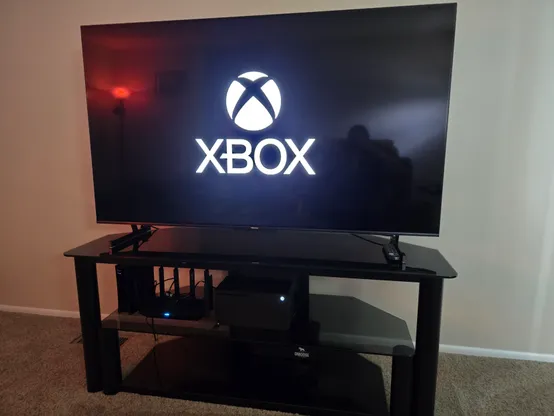 An Xbox setup in a TV stand with the television displaying the Xbox logo. 