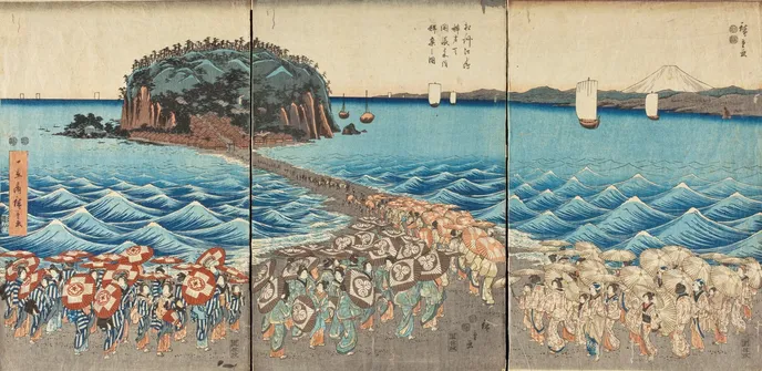 A crowd of female entertainers walk along a beach and across a land bridge to Enoshima, an island a short distance off the shore. In the background you can see Mt Fuji.