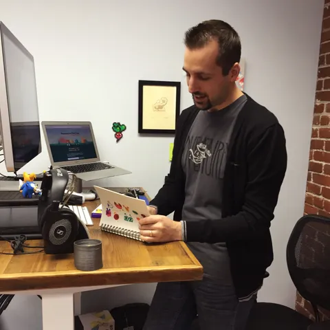 The author at a standing desk, drawing in a sketchbook while talking.