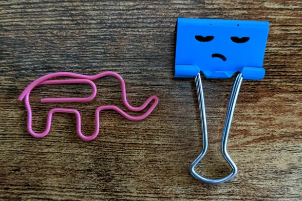 A pink elephant-shaped paperclip and a blue binder clip with a grumpy face on it.

In the right hands, these are powerful tools.