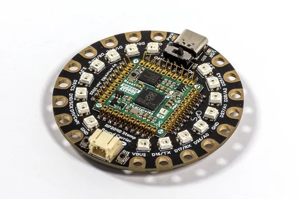 a round pcb with an rp2040 stamp in the middle, held by FlexyPins, and a ring on neopixels and alligator clip-friendly pads around it