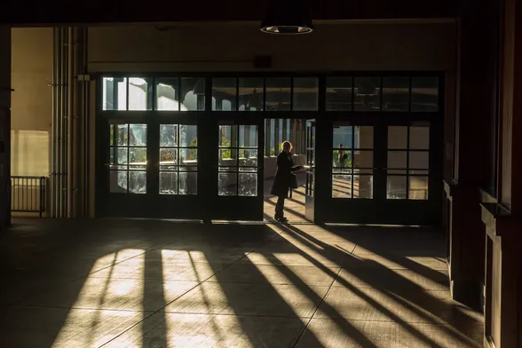 Woman entering a doorway in a train station, caught in a sunbeam