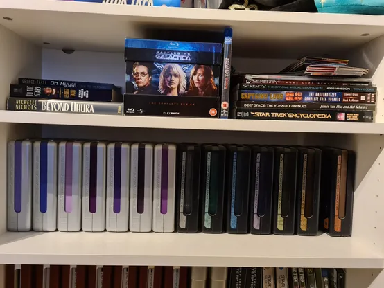 Bookcase filled with Star Trek DVDs and books and a Battlestar Galactica Bluray boxset. 