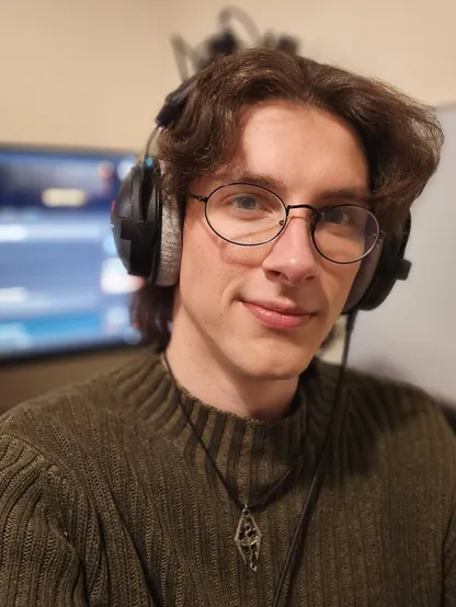 Me posing for a selfie in a green sweater with a Skyrim themed necklace