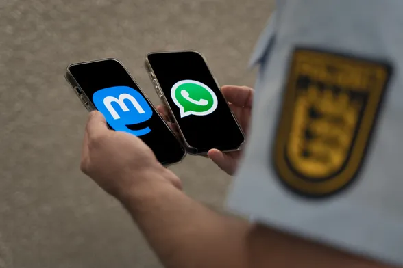 Polizist hält zwei Smartphones mit Logos WhatsApp und Mastodon in den Händen