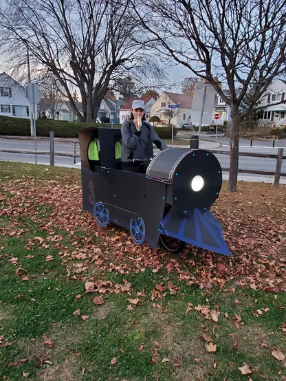 A photo of me sitting on my cargo bike that is decorated with cardboard to look like a steam locomotive