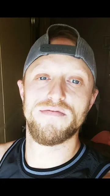 Photo of a guy with backwards hat, blue basketball jersey and goatee/mustache.