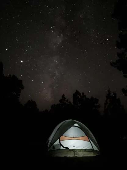 Spent the night camping at Berlin-Ichthyosaur State Park and took advantage of the pure dark night sky to take a photo of the Milky Way above my dimly lit green, white, and orange tent. Dark trees surrounding my camp site mark the edge of the photo as the brilliant stars above shine brightly in the image.