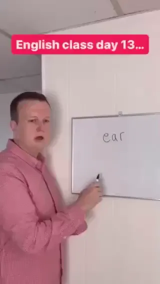 A man stands at a whiteboard, writing the words he’s teaching. The same man in a different outfit sits at a desk with a pen and paper. The camera switches back and forth between the shots as if the teacher and student are different people. The student keeps looking highly confused. 