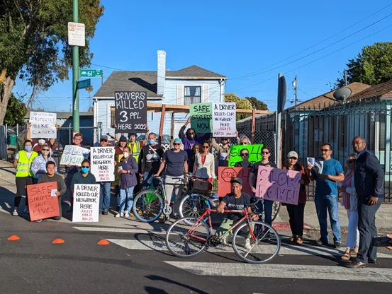 Group of activists at 61st and Bancroft holding up signs saying a Driver Killed Our Neighbor Here