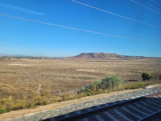 A small hill in the middle of a flat steppe. Blue sky.