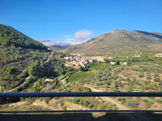 Village in the middle of the mountains, surrounded by green trees/bushes.