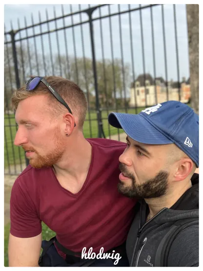 Tristan is wearing his sunglasses and a red T-shirt. He's sitting on top of me, and I'm wearing my famous blue cap. We're both in profile, wearing our beards - he in red, me in chestnut. Our faces exude well-being.