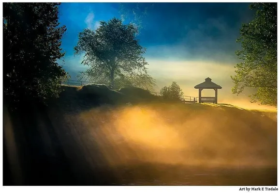 Photograph of a misty morning with brilliant light reflecting off the mists over a body of water. On the opposite shore a gazebo is in silhouette. 