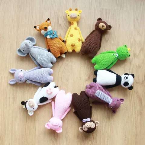 Picture of 11 crocheted animals posed in a circle. The animals are, clockwise, a giraffe, a brown bear, a grumpy frog with a crown, a panda, a purple dragon, a monkey with a bow tie, a pig, a cow, a purple rabbit with wings, an elephant and a fox with a blue scarf.