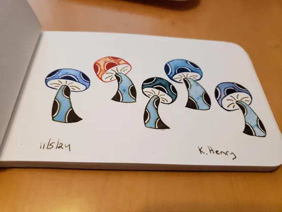 Hand drawn generative/procedural art in ink on an open page of my sketchbook. The abstract pattern looks like five mushrooms with polka dots on their stems and caps.
