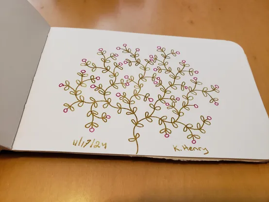 Hand drawn generative art in ink on an open page of my sketchbook. The abstract pattern looks a bit like  a shrub with flowers or fruits on it.