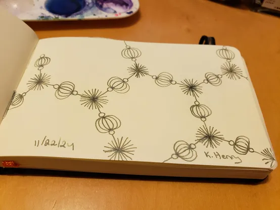 Hand drawn generative/procedural art in ink on an open page of my sketchbook. The abstract pattern looks a bit like a chemistry diagram with fancy beads.