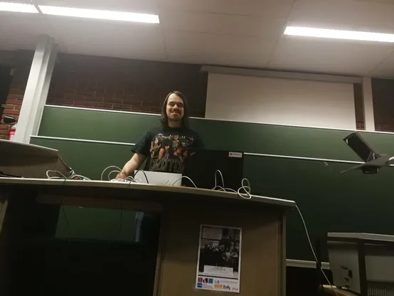 A nerd right before giving his talk, waiting for the break between talks to end, failing at smiling into the camera.