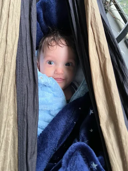 A smiling baby inside a hammock.