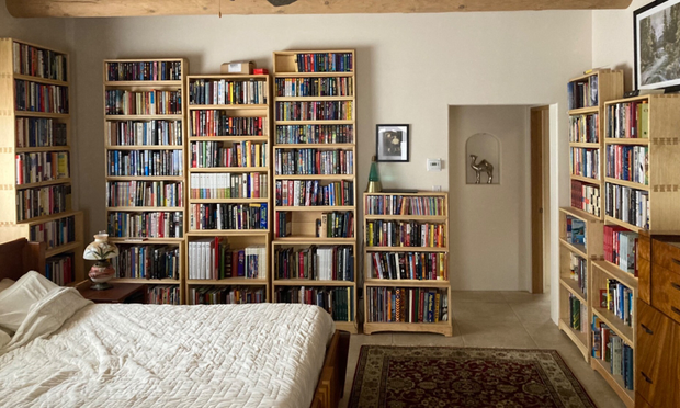 A bedroom with many cases of books along the walls.