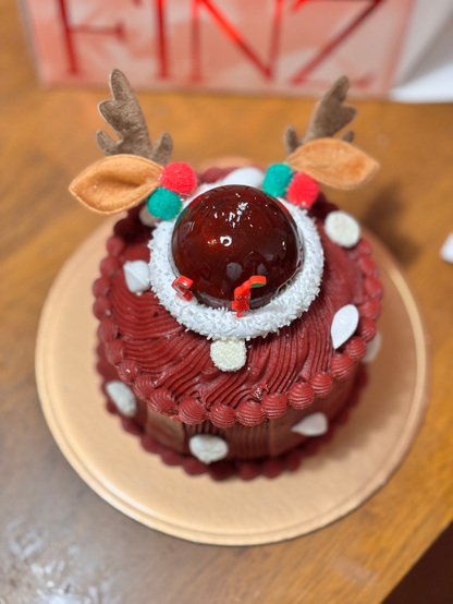 A Christmas cake shaped like the face of Rudolph the Red-Nosed Reindeer.