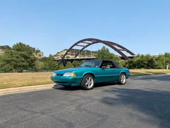 1993 Mustang convertible in Calypso green parked in the shadow of the Pennybacker Bridge in Austin, TX