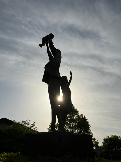 A statue stands silhouetted against the evening sun.