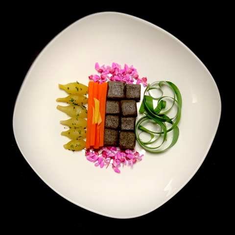 Black background. White plate is irregularly rounded square tuned on its side like a wonky diamond.

On the left are steamed daylily bulbs facing so the stem end points left.
They look like dark yellow bowling pins.

They were steamed for 20' in bamboo
tray and then infused with kombu dashi ( mirin, usukuchi soy, culantro) for ~ 3
hours. Then sprinkled with more dried culantro. Just steamed, they taste like asparagus and pearl onion. Infused, the culantro was a mistake, it didn't blend well.

Second to left are thinly sliced carrots standing in a row. Steamed and infused with kombu dashi but with ginger, mirin and usukuchi soy. There are three ginger sticks on top.

Second to right are 8 square acorn noodles. They mostly just tasted like wheat noodles.

Right, curled green daylily leaves.
Top and bottom, clusters of small dark pink redbud flowers.

Kombu dashi recipes were based on Nobu's Vegetarian cooking, p.48-49.