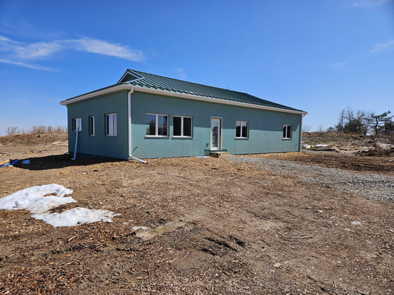 March 22, 2024 It needs landscaping and the permanent front door, and the front stoop and ramp, but the outside is basically done. The inside is progressing