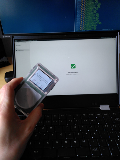 tangara held up in front of a laptop screen. The laptop screen is displaying a "Flash complete" success message. The tangara is informing us that it is indexing the database for the first time.