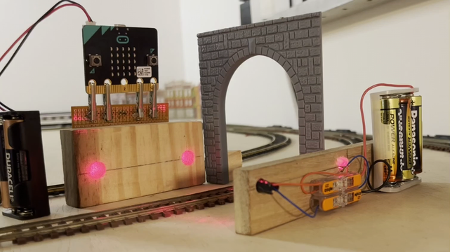 Video showing two lasers illuminating sensors on the other side of H0-scale train tracks. The sensors are read by a micro:bit board that measures and displays the speed of the train converted to real scale. A 4-car SBB passenger train pulled by an Re460 locomotive goes by at 209km/h. 