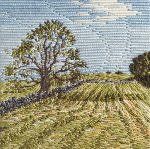 Stitched artwork depicting a hayfield with waving lines of cut hay. A tree to the left casts a shadow across the field