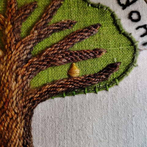 A golden oblong fruit hangs from a tree branch.