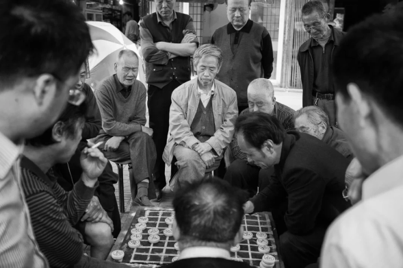 A group of men around a board game on the street