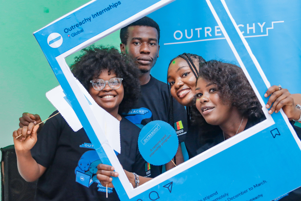 Four African Outreachy interns pose behind an Outreachy photo frame. This is from the 2024 1,000 Outreachy intern celebration.