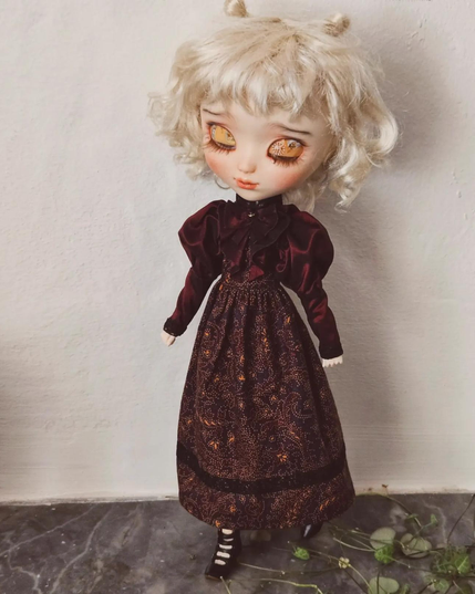 A whitehaired doll with a victorian dress. 
The dress has bug puffed slives and a big bow in a silky fabric.