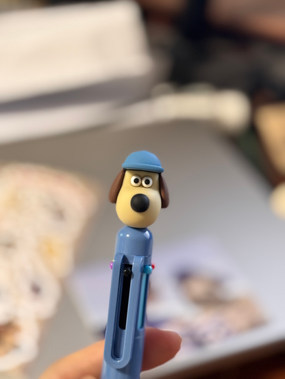 A ballpoint pen with the head of a Gromit wearing a hat attached to it