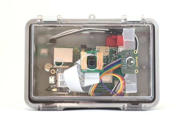 Frontal de la cámara en al que se ve el modulo para fotografias como el GPS y el altímetro adheridos a la tapa transparente de la caja.