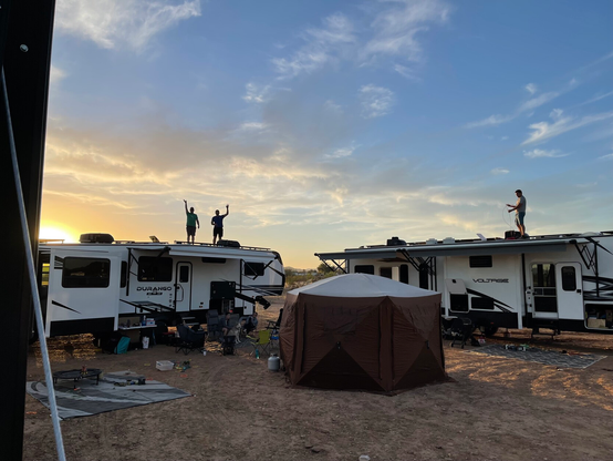 Our friends waving to us from on top of their rigs while we do a big custom solar palooza electrical install in the desert.